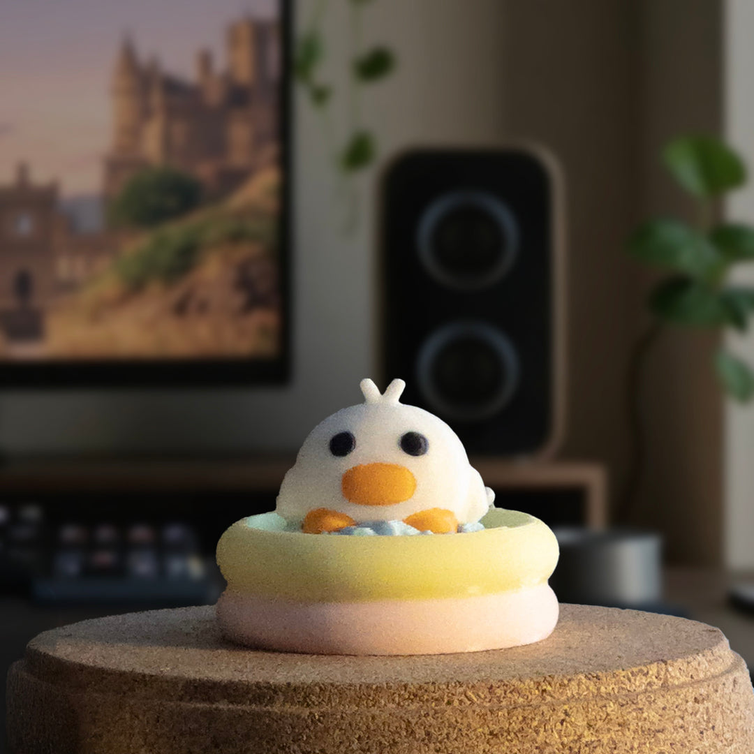 A cute duck charm with a round beak relaxing inside a pastel-colored inflatable pool, displayed on a tabletop.