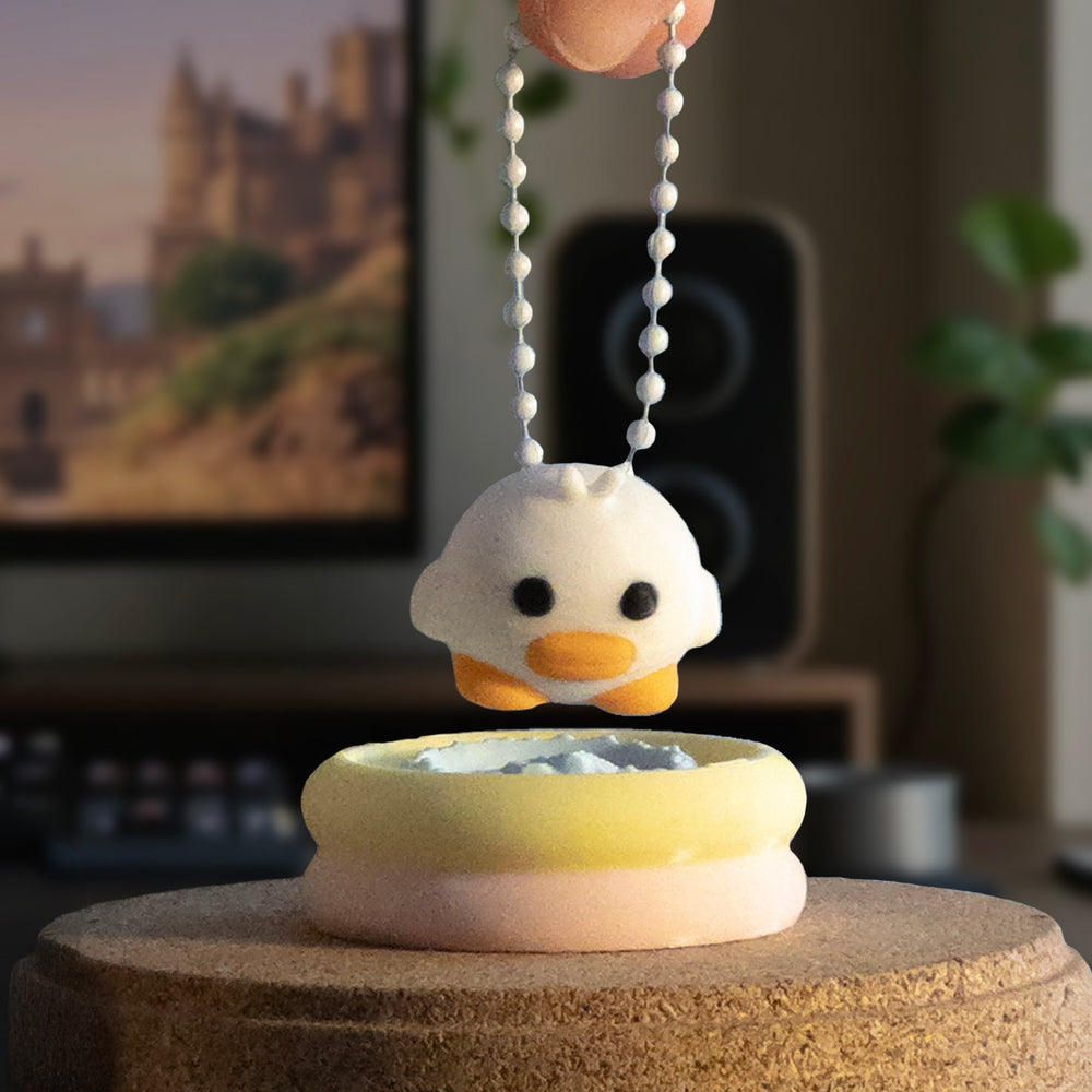 A small duck charm being held by a keychain above a pastel inflatable pool base, ready to be placed back in.